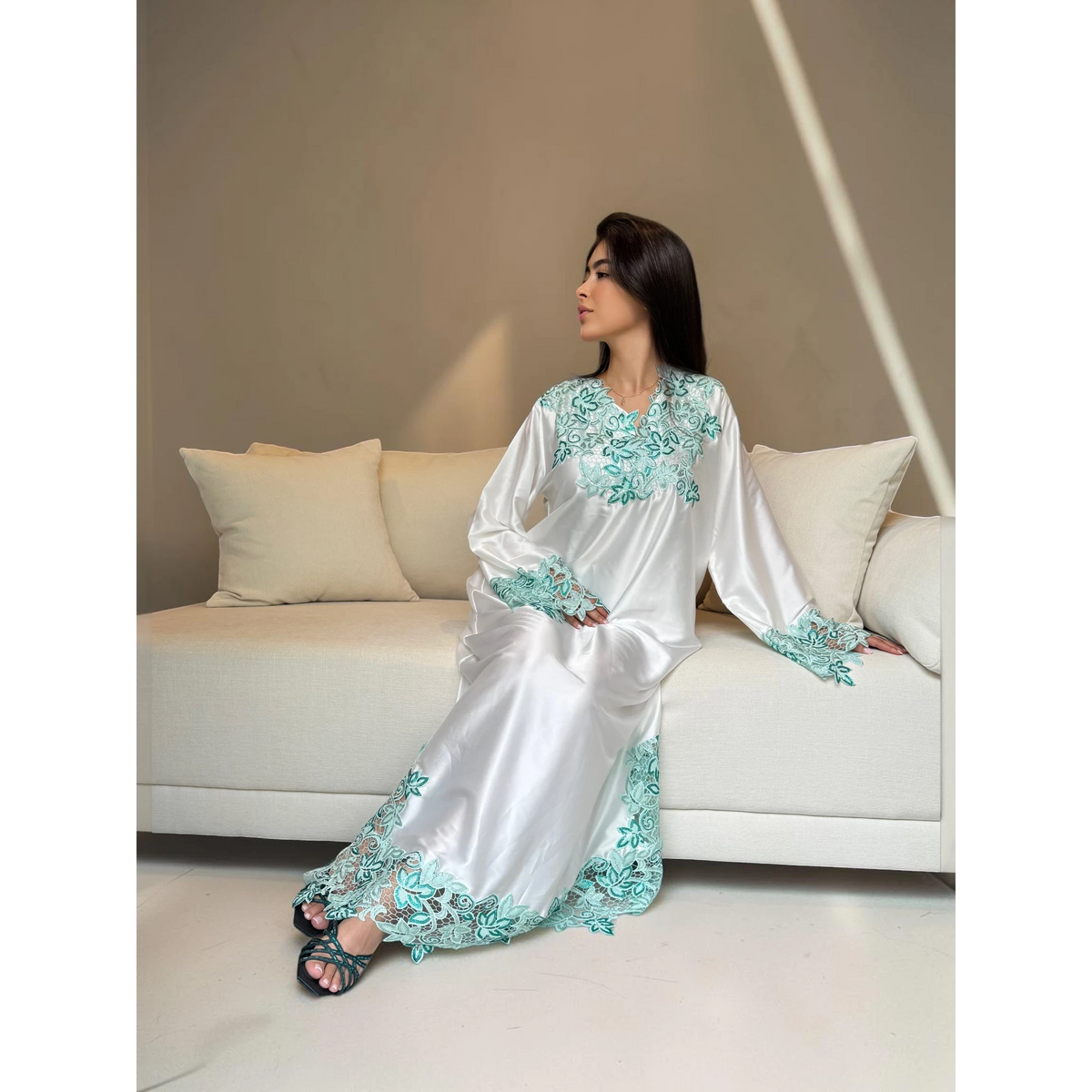 ABAYAS white Nida lace dress with emerald and turquoise floral embroidery on neckline, sleeves, and hem. Long sleeves, floor length.